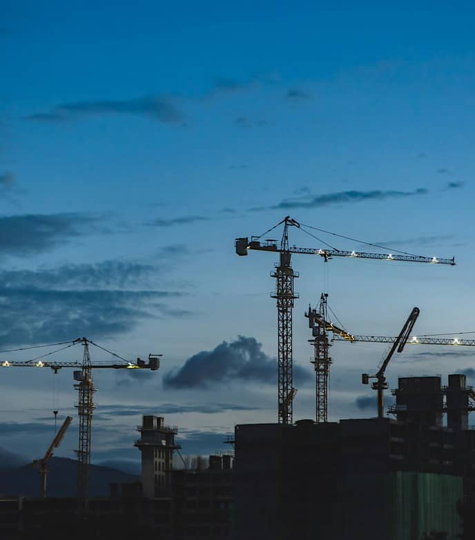 Grúas de construcción en una obra al atardecer