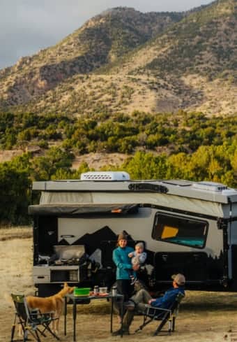 Familia relajándose junto a su camper en las montañas